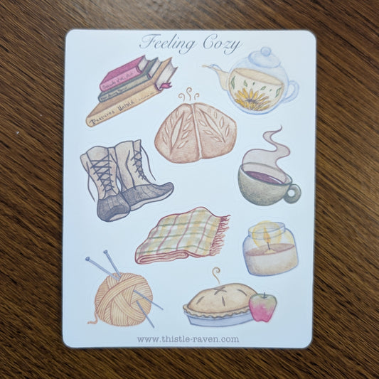 Sticker Sheet with illustrations of cozy items like a book, tea, and plaid blanket on a wooden surface.